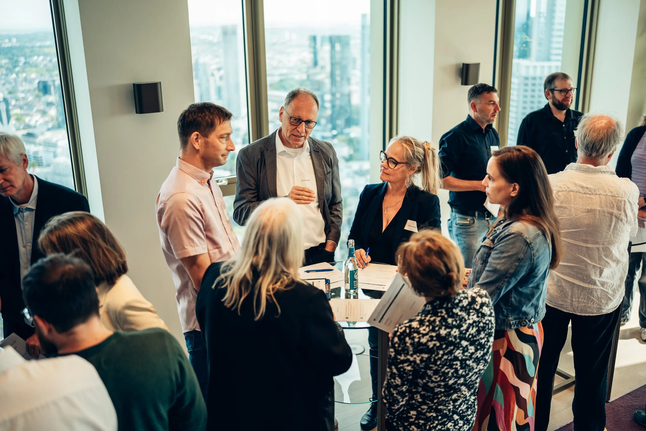 Teilnehmende eines Workshops im Gespräch in kleinen Gruppen, hinter ihnen der Blick über die Stadt
